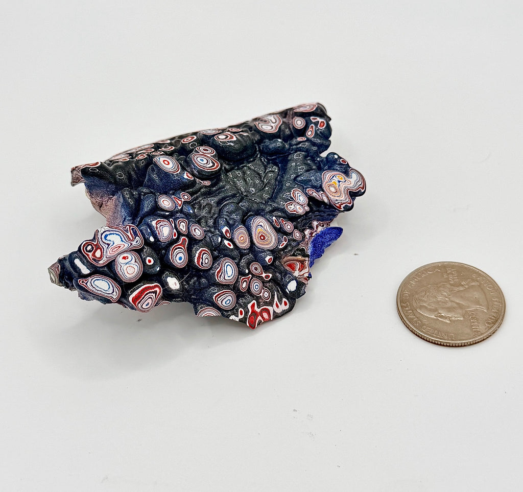 Vintage Kenworth Fordite piece showing layered red, white, blue and dark automotive paint patterns