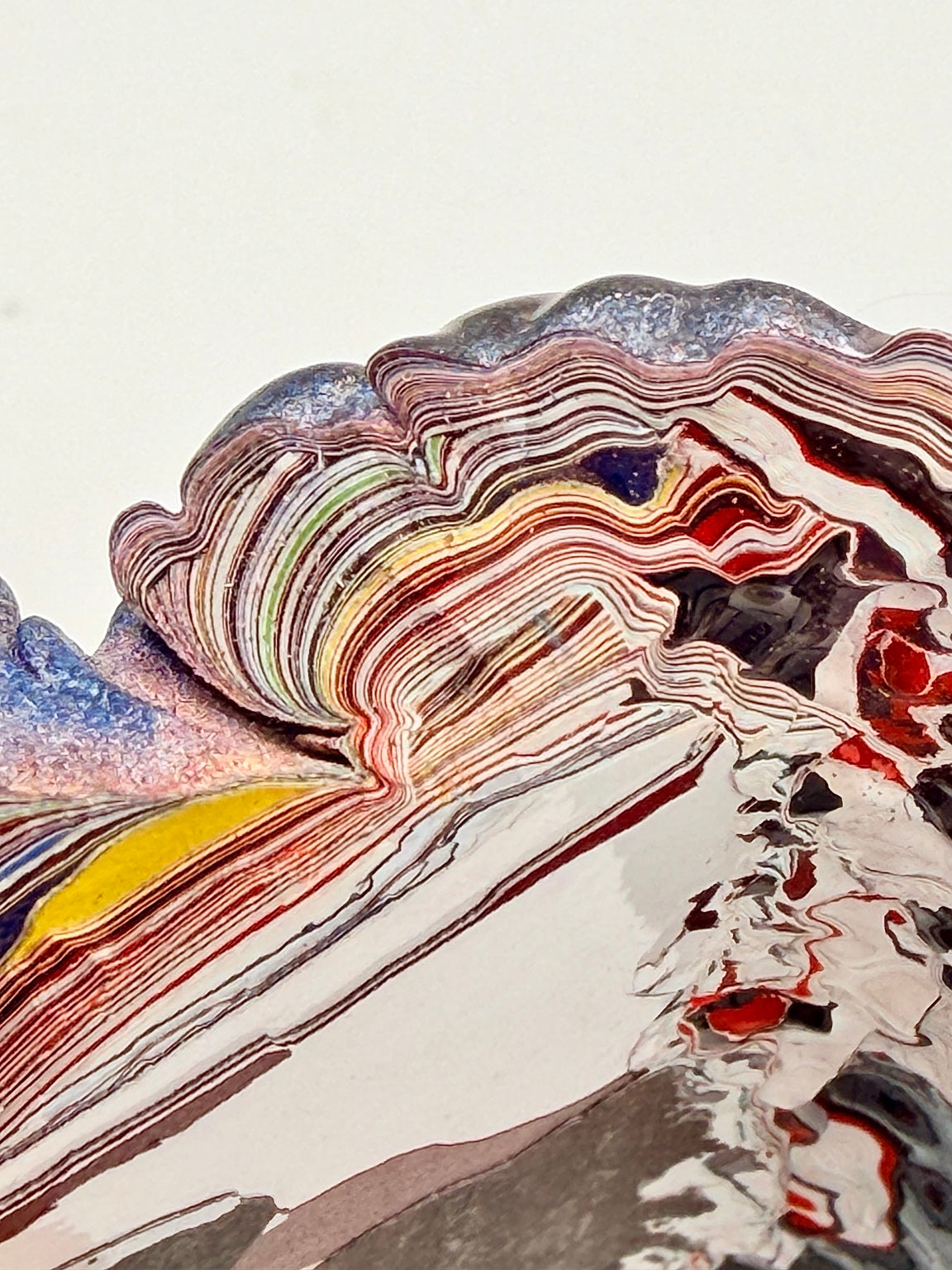 Macro close-up of vintage Kenworth Fordite revealing tightly layered multicolor automotive paint